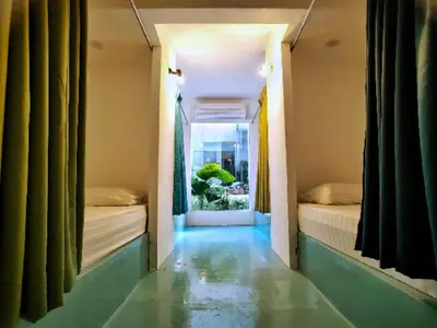 a hallway with two beds in a room with a window at Beds In Garden Hostel in Ipoh