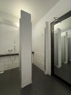 a bathroom with a mirror and white tiled walls at Beds In Garden Hostel in Ipoh