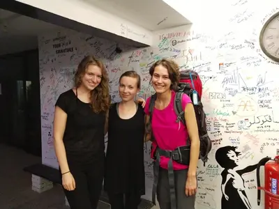 three women standing in front of a wall with graffiti at Beds In Garden Hostel in Ipoh