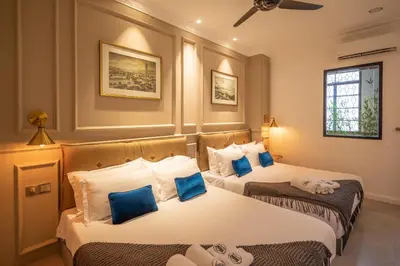 two beds in a hotel room with blue pillows at Manhattan Residence in George Town
