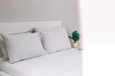 a white bed with white pillows and a plant at TheDaun Homestay Seri Iskandar, Perak in Seri Iskandar