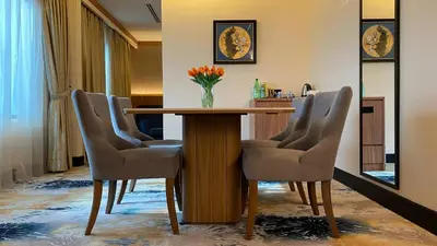 a dining room table with chairs and a vase of flowers on it at Kinta Riverfront Hotel & Suites in Ipoh
