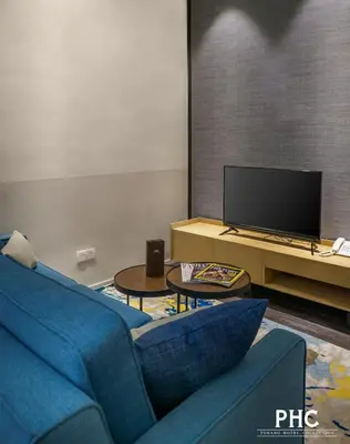 a living room with a blue couch and a tv at Bahari Parade Hotel Managed by The Ascott Limited in George Town