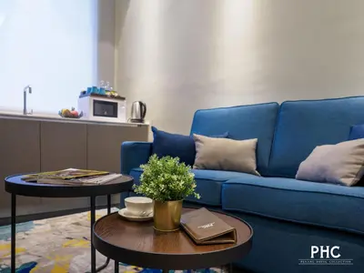 a living room with a blue couch and a table at Ropewalk Piazza Hotel Managed by The Ascott Limited in George Town