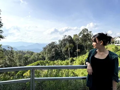 a woman standing on a fence looking at the forest at Wyndham Garden Shahzan Fraser's Hill in Bukit Fraser