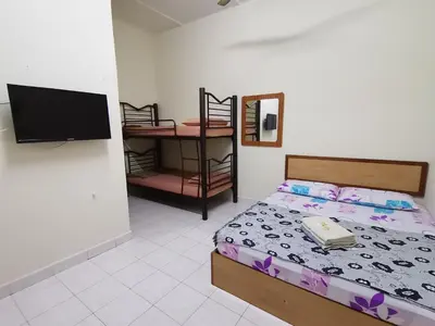 a bedroom with a bed and a tv and a table at Nipahmas Chalet in Pangkor