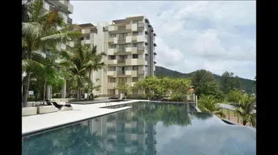 a hotel with a swimming pool in front of a building at By the sea Beach BABY in Batu Ferringhi