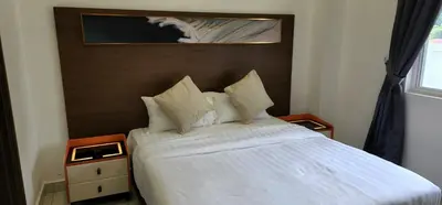a bedroom with a large bed with a wooden headboard at Zinnia Residence Tanah Rata in Cameron Highlands