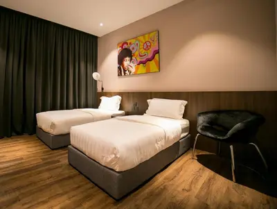 a hotel room with two beds and a chair at Eureka Hotel Penang in Bayan Lepas