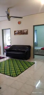 a black leather couch in a living room with a green rug at Cameron Highlands Muslim Apartment by AziziCameron in Cameron Highlands