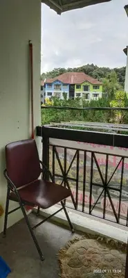 a brown chair sitting on a balcony with a view at Cameron Highlands Muslim Apartment by AziziCameron in Cameron Highlands