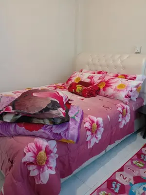 a bed with a pink comforter with flowers on it at Cameron Highlands Muslim Apartment by AziziCameron in Cameron Highlands