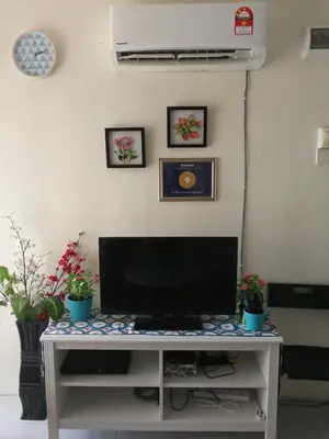 a desk with a television and two potted plants at A1-04-03 Damiana Apartment in Tanjung Malim