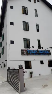 a white building with a blue sign on it at TULIP HOTEL & APARTMENT in Cameron Highlands