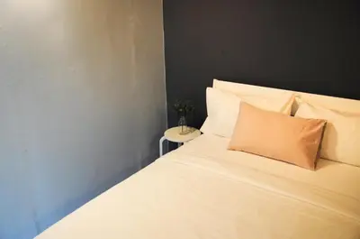 a white bed with an orange pillow on it at GRAYHAUS SOHO Ipoh in Ipoh