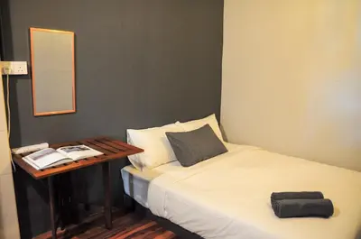 a small bedroom with a bed and a table at GRAYHAUS SOHO Ipoh in Ipoh