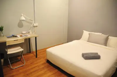 a bedroom with a bed and a desk and a bed and a lamp at GRAYHAUS SOHO Ipoh in Ipoh