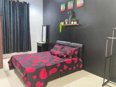 a bedroom with a bed with a red and black bedspread at Abg Long Fadhil Homestay in Sungai Petani