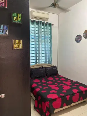 a bedroom with a bed with a black and pink comforter at Abg Long Fadhil Homestay in Sungai Petani