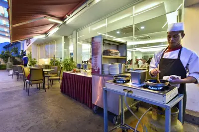 a man cooking food on a stove in a restaurant at Hotel Sentral Georgetown @ City Centre in George Town