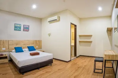 a bedroom with a bed with blue pillows and a table at Northern Lodge Hotel in Sungai Petani