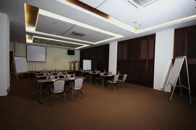 a conference room with tables and chairs and a screen at Aroma Hotel in Butterworth
