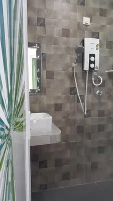 a bathroom with a shower with a sink and a mirror at Ipoh EastEden Homestay in Ipoh