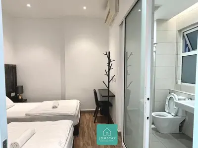 a hotel room with two beds and a toilet at JOMSTAY Octagon Palm Suites Ipoh in Ipoh