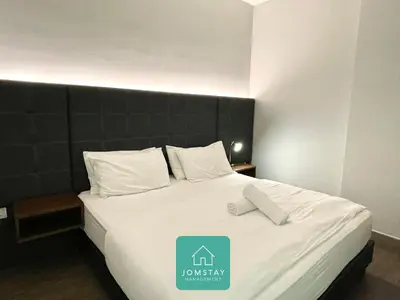 a bedroom with a large bed with white sheets and pillows at JOMSTAY Octagon Palm Suites Ipoh in Ipoh