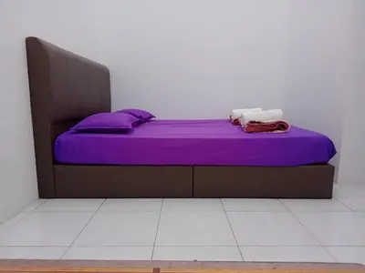 a bed in a room with purple sheets and pillows at Wany Homestay & Guest House in Sungai Petani