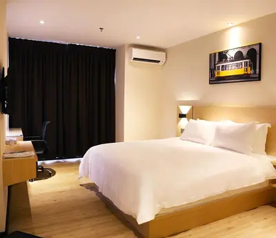a bedroom with a large white bed and a desk at Rivertel in Teluk Intan