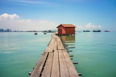 a dock with a red building on the water at 118 Hotel Macalister in George Town