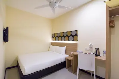 a small room with a bed and a desk with a table at 118 Hotel Macalister in George Town
