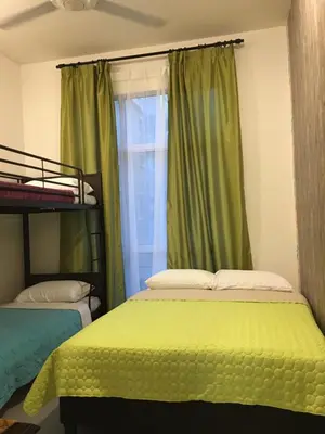 two beds in a room with green curtains and a window at Aalina's Comfort Home - Muslim Homestay in Cameron Highlands