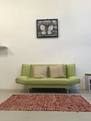 a green couch in a room with a picture of a butterfly at Aalina's Comfort Home - Muslim Homestay in Cameron Highlands