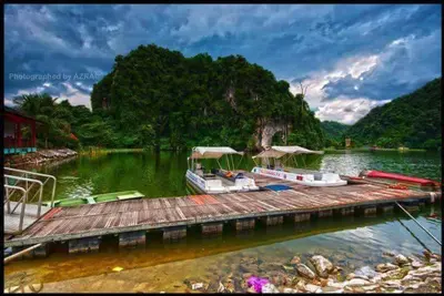 two boats are docked at a dock on a river at Homestay D-Zara in Ipoh