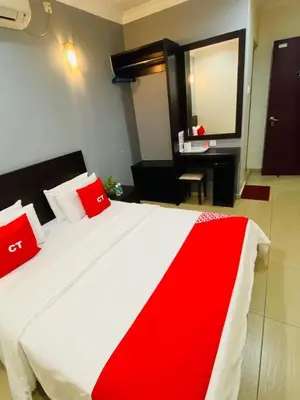 a bedroom with a bed with red pillows and a mirror at Ct Hotel in Sitiawan