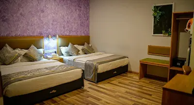 two beds in a hotel room with purple walls at K GARDEN HOTEL (IPOH) SDN BHD in Ipoh