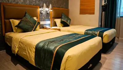 two beds in a hotel room with yellow and green sheets at K GARDEN HOTEL (IPOH) SDN BHD in Ipoh