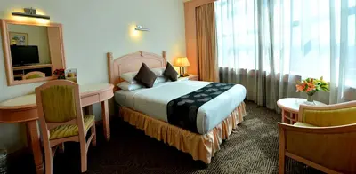a hotel room with a bed and a desk and a mirror at Emerald Puteri Hotel in Sungai Petani
