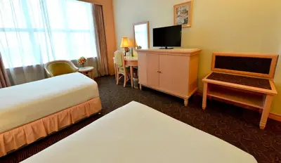 a hotel room with two beds and a desk with a television at Emerald Puteri Hotel in Sungai Petani