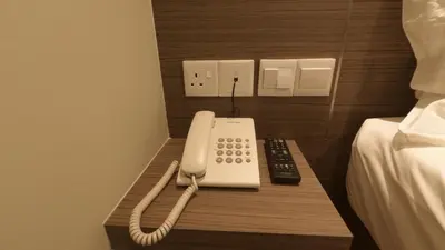 a phone sitting on a table next to a bed at U Design Hotel Kuala Lipis in Kuala Lipis