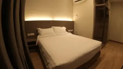 a bedroom with a white bed with a wooden headboard at U Design Hotel Kuala Lipis in Kuala Lipis