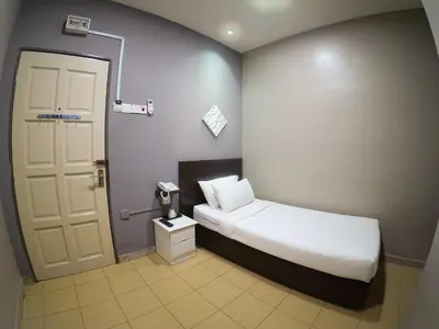 a small bedroom with a bed and a door at JV Hotel @ Bandar Tasek Mutiara in Simpang Ampat
