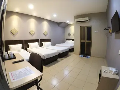 a hotel room with three beds and a desk at JV Hotel @ Bandar Tasek Mutiara in Simpang Ampat