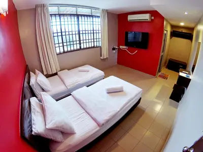 a bedroom with two beds and a red wall at JV Hotel @ Simpang Ampat in Simpang Ampat