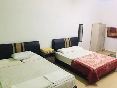 a room with two beds and a cabinet in it at Bunga Raya Guest House BALING in Baling