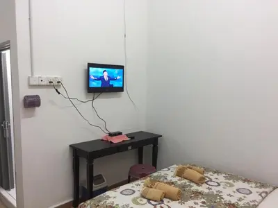 a room with a bed and a tv on a wall at Bunga Raya Guest House BALING in Baling