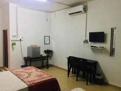 a bedroom with a bed and a table and a television at Bunga Raya Guest House BALING in Baling