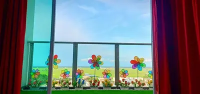 a window with a view of a garden with flowers at WindMill SunRise PaddyView Homestay in Sekincan
